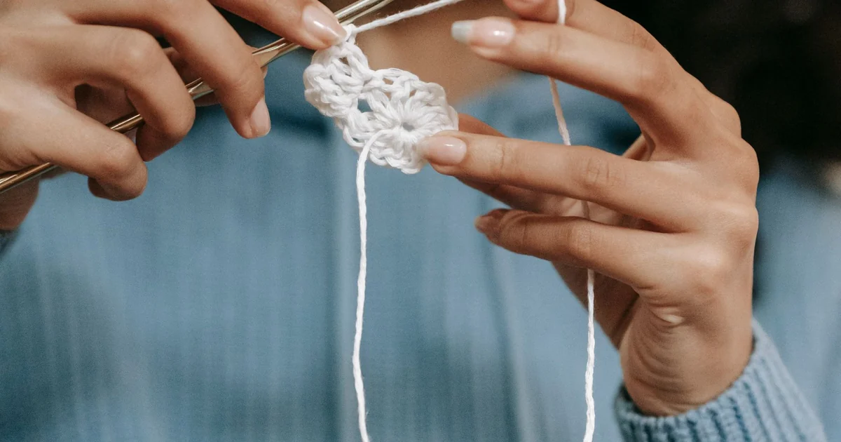 Hands making a small light crochet rectangle with a hook.
