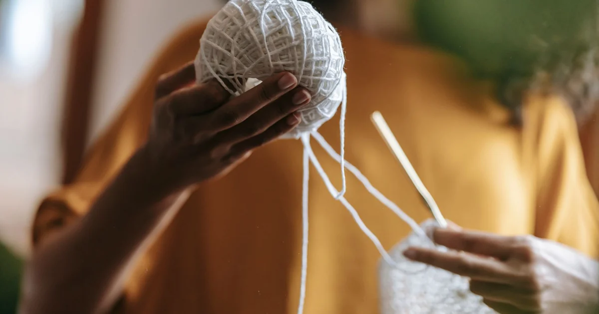 Hands gently shaping a light crochet motif on a flat surface.