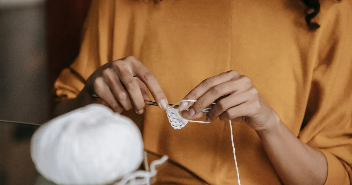 Hands holding a crochet row with the first stitch marked by a hook.