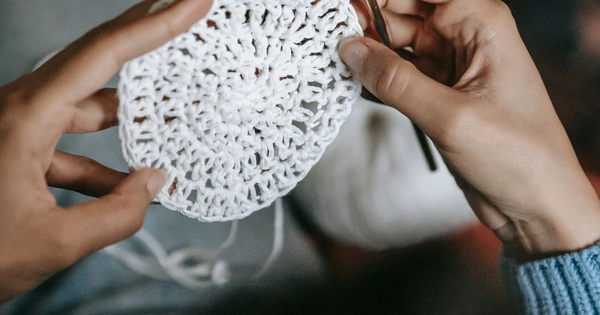 Hands holding a white circular crochet piece.