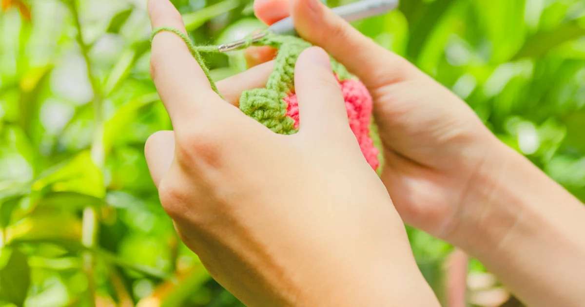 Hands measuring a pale crochet swatch.
